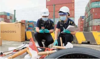  ??  ?? Chen Wei (right) and her colleague discover a lithium battery inside an e-bike. — Jiang Xiaowei