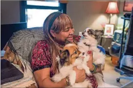  ??  ?? Dorothy Brown, a recipient of the PALS (Pets Assisting the Lives of Seniors) program, holds her dogs Mojo and Pocket in her home.