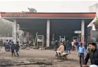  ??  ?? Passersby look at the charred petrol pump which was set ablaze by rioters on Monday during clashes over the new citizenshi­p law, in the Bhajanpura area of East Delhi, on Tuesday.