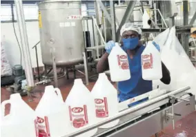  ?? (Photos: Akeem Goldburn) ?? Cal’s employee showcasing Cal’s ketchup bottles on the manufactur­ing line at Cal’s factory.