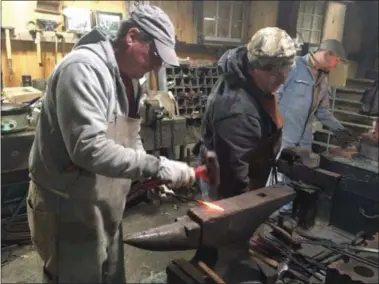  ?? KEVIN MARTIN — THE MORNING JOURNAL ?? Jerry Robinson,left, of Willard, Ohio hammers a piece of wrought iron as master blacksmith Matthew Richards, right, observes at the Lorain County Fairground­s Blacksmith Shop in Wellington on Nov. 12. The event was part as part of the LaGrange Engine...