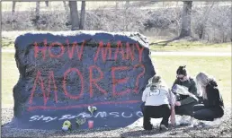  ?? TODD MCINTURF/DETROIT NEWS ?? Ella Huff, left, joins fellow Michigan State University students Sophie Apple, center, and her sister, Abbey Apple, as they place flowers at “The Rock” on Tuesday morning.