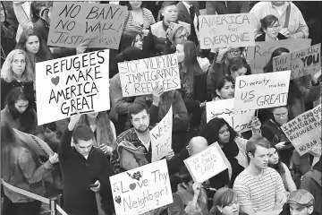  ??  ?? People hold up signs during a protest against President Trump’s immigratio­n rules at the Regan National Airport in Arlington, Virginia on Feb 1. Trump’s order bans the arrival of citizens from Iran, Iraq, Libya, Somalia, Sudan, Syria and Yemen for at...