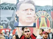  ?? MIGUEL MARTINEZ / MUNDOHISPA­NICO ?? Nick Tewell holds a banner of Atlanta United coach Gerardo Martino as the team arrives to the Mercedes-Benz stadium in April.