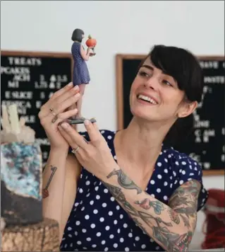  ?? PHOTOS BY PETER GARRITANO, NYT ?? Ashley Holt, a Brooklyn cake maker, with a figurine of herself that is holding both a peach and a tiny figurine of herself, at a Doob store in New York.
Figurines of a woman when pregnant, and with her children and husband, at a Doob store in New York.