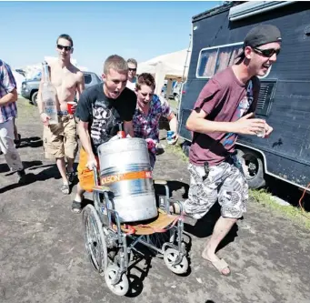  ?? JASON FRANSON/Postmedia News file photo ?? Partiers wheel out a keg of beer at the Big Valley Jamboree in Alberta. A student-run U of S campaign is urging an end to a daredevil binge drinking game called Neknominat­ions in which people are recorded attempting boozefuell­ed dares that are then...