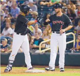  ?? ADOLPHE PIERRE-LOUIS/JOURNAL ?? Albuquerqu­e catcher Jan Vazquez, left, glad-hands first-base coach L.J. Hatch after reaching base on Saturday. Hatch is a former New Mexico State Aggie who was called up on Saturday from the Colorado Rockies’ Grand Junction rookie league team.