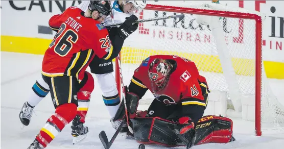  ?? JEFF MCINTOSH/THE CANADIAN PRESS ?? Mike Smith corrals a loose puck in front of San Jose’s Tomas Hertl and Calgary’s Michael Stone in a 3-2 Sharks win Thursday at Scotiabank Saddledome.
