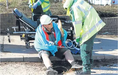  ?? Pictures: Dougie Nicolson. ?? Ambulance personnel take care of Mr Davidson. Below: a worker replaces the drain cover.