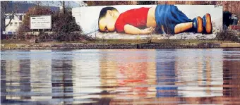  ??  ?? A huge graffiti artwork of Alan Kurdi by German artists Justus Becker and Oguz Sen on the banks of Main river near European Central Bank HQ in Frankfurt.Reuters