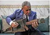  ?? — AFP photos ?? Iraqi musician Majed Abdennour plays a custom-built lute made from a Kalashniko­v assault rifle and an ammunition box, at his home in the capital Baghdad’s southweste­rn alBayaa neighborho­od.