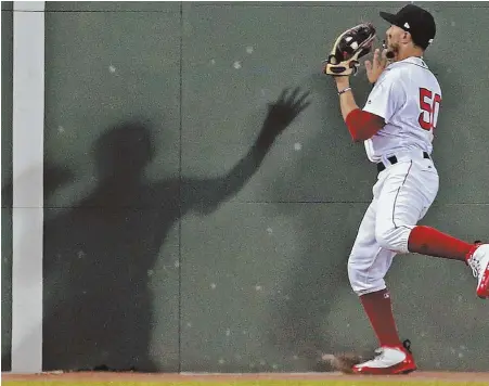  ?? STAFF PHOTOS BY MATT STONE ?? MAKING AN IMPRESSION: Mookie Betts casts a shadow on the wall in center field last night at Fenway after making a catch on the warning track as the Red Sox tried to complete a four-game sweep of the Yankees; at right, J.D. Martinez reacts after striking out.