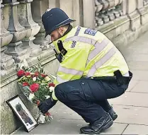  ??  ?? SOLEMN A police officer lays a floral tribute to Keith, pictured left
