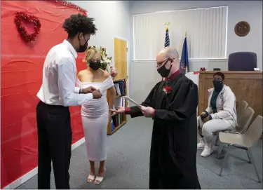  ?? BEN HASTY — MEDIANEWS GROUP ?? District Judge Eric J. Taylor hands Daquane Williams and Trisha Jayn Williams, their wedding rings during their marriage ceremony in Taylor’s West Reading courtroom where he spent Valentine’s Day performing wedding ceremonies.