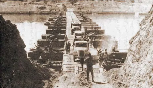  ??  ?? Des camions égyptiens traversent l'un des six ponts d'assaut sur le canal de Suez. Leur attaque par voie aérienne s'avérera particuliè­rement difficile. (© D.R.)