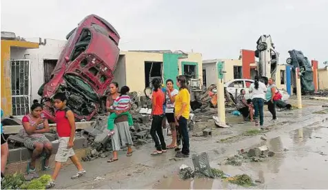  ?? Reuters ?? Homes destroyed Residents stand outside their homes amid damaged cars after a tornado hit the town of Ciudad Acuna in Mexico. The tornado’s path of destructio­n stretched 1.8km through the city.