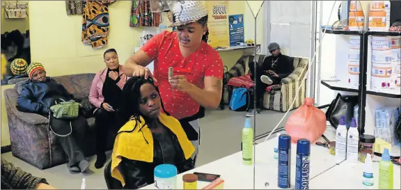  ??  ?? KING OF DREADS: Television extra turned dreadlock stylist extraordin­aire Siya Cembi performs his magic on regular customer Akhona Mdutyulwa at God’s Blessings Salon in the city centre