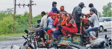  ??  ?? ↑
People gather to travel on a threewheel­er during rain in Ahmedabad, Gujarat, on Thursday.
Agence France-presse