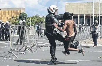  ??  ?? Un policía pelea con un manifestan­te, en la Explanada de los Ministerio­s, en Brasilia, donde se cometieron actos de vandalismo en las sedes de Agricultur­a, Cultura, Planeación y Medio Ambiente.