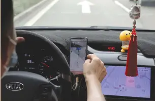  ?? (Tingshu Wang/Reuters) ?? A DRIVER of Chinese ride-hailing service Didi drives with a phone showing a navigation map on Didi’s app, yesterday in Beijing.