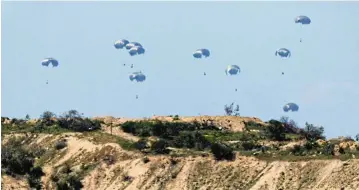 ?? /Reuters ?? Desperate measures: Aid packages fall towards northern Gaza, after being dropped from an Egyptian military aircraft, as seen from Israel’s southern border yesterday.