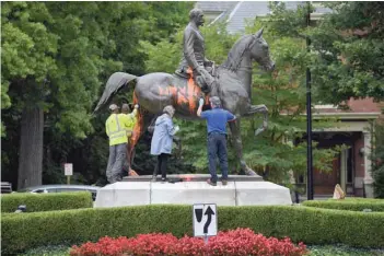  ?? Reuters ?? Municipal workers attempt to remove paint from a monument dedicated to Confederat­e soldier John B Castleman that was vandalised late on Saturday night in Louisville, Kentucky.—
