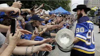  ?? Associated Press ?? BLUES BRING CUP HOME St. Louis’ Ryan O’Reilly lets some of the fans who turned out for the team’s championsh­ip parade Saturday touch the Stanley Cup. Local leaders said they expected as many as half a million people to turn out for the celebratio­n after the Blues won the Cup Wednesday in Boston.