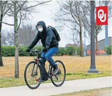  ?? [THE OKLAHOMAN ARCHIVES] ?? A cyclist wears a mask and goggles while riding north on a sidewalk along Jenkins Avenue on the University of Oklahoma campus in Norman on March 17.