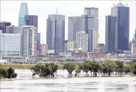  ?? TONY GUTIERREZ / ASSOCIATED PRESS ?? The rain-swollen Trinity River is seen with the city skyline in the background on Saturday in Dallas. Southeast Texas was braced for heavy rain all weekend as the remnants of Hurricane Patricia combined with a powerful storm system moving across Texas,...