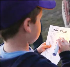  ?? Nikolas Samuels/The Signal ?? Eight-year-old Wyatt Overstreet looks at a list of the victims from the Las Vegas shooting during a vigil held at Santa Clarita Marketplac­e Park on Wednesday.