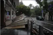  ?? VINCENT YU — THE ASSOCIATED PRESS ?? A collapsed wooden wall caused by Typhoon Hato sit on a street in Hong Kong, Wednesday. The powerful typhoon barreled into Hong Kong on Wednesday, forcing offices and schools to close and leaving flooded streets, shattered windows and hundreds of...