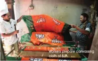  ?? Workers prepare canvassing cloth of BJP ??