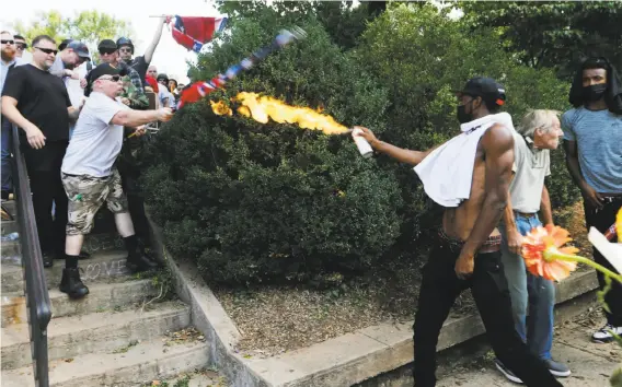  ?? Steve Helber / Associated Press ?? CHARLOTTES­VILLE, VA., AUG. 12: A counterdem­onstrator uses a lighted spray can against a white nationalis­t demonstrat­or at the entrance to Emancipati­on Park.