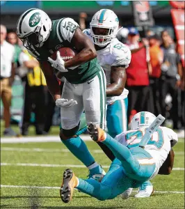  ?? MICHAEL OWENS / GETTY IMAGES ?? Dolphins safety Reshad Jones (20) can’t keep Jets running back Bilal Powell from scoring in the third quarter during Sunday’s 20-12 Miami win.