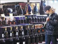  ?? WANG GANG / CHINA NEWS SERVICE ?? Left: A customer walks past an array of imported alcoholic products at a supermarke­t in Hangzhou, capital of Zhejiang province.