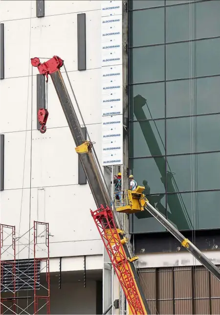  ??  ?? Staying alert: A worker watches from a crane as his work mate attends to a task in a high rise building in Kl. Workers must be constantly reminded on the importance of safety as a slip can prove to be fatal.