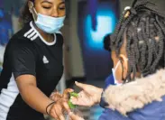  ?? Jessica Christian / The Chronicle ?? Teacher Brajae Jones gives a student a squirt of sanitizer at Freedom School, a Marin City program.