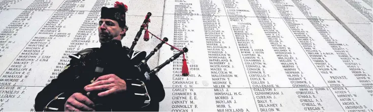  ??  ?? A piper plays a lament in front of the names of the thousands of British and Commonweal­th soldiers who died in the First World War.