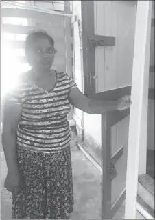  ??  ?? Chatterpau­l Persaud’s mother, Hemwattie Persaud holding the piece of wood from the door that the bandits removed in order to enter the house.