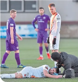  ??  ?? Stenhousem­uir’s Adam Mccracken receives treatment after suffering a kick in the face