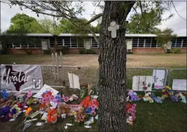  ?? ERIC GAY — THE ASSOCIATED PRESS FILE ?? A cross hangs on a tree at Robb Elementary School on in Uvalde, Texas, where a memorial has been created to honor the victims killed in the recent school shooting.