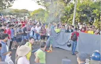  ??  ?? Un grupo de manifestan­tes declarados “profamilia” prende fuego a una bandera del movimiento LGBT durante los incidentes que se registraro­n ayer en la ciudad de Hernandari­as.