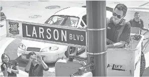  ?? MATT KRYGER/THE INDIANAPOL­IS STAR ?? For the upcoming Brickyard 400 race, Kyle Larson put up a Larson Blvd street sign Wednesday in downtown Indianapol­is. Some streets have been temporaril­y changed to a NASCAR driver’s last name.