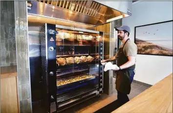  ?? Christian Abraham / Hearst Connecticu­t Media ?? Owner Ben Pote checks on chickens cooking at Wildacre Rotisserie at 147 E. Putnam Ave. on June 21. Pote’s launching a chicken challenge at Wildacre, daring diners to eat 41 rotisserie chickens in 41 days.