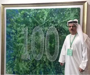  ??  ?? Mohammed Mandi with his centenary art piece displayed at the entrance of the ADIBF.