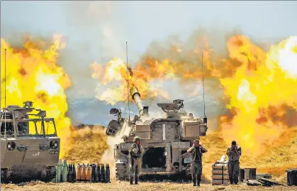  ?? AGENCIES ?? An Israeli artillery unit (top) fires towards Gaza Strip; people (below, left) walk by a bombed tower in Gaza; a shattered photo frame in Israel’s rocket-hit Petah Tikva.