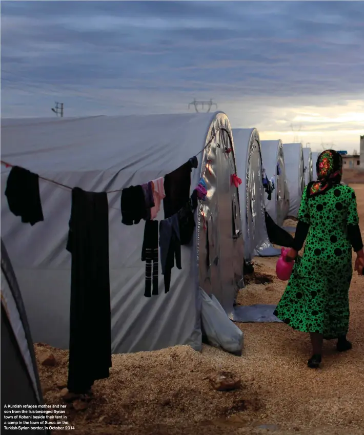  ??  ?? A Kurdish refugee mother and her son from the Isis-besieged Syrian town of Kobani beside their tent in a camp in the town of Suruc on the Turkish-Syrian border, in October 2014