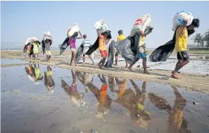  ?? REUTERS ?? Rohingya refugee workers carry bags of salt as they work in processing yard in Cox’s Bazar, Bangladesh on April 12.