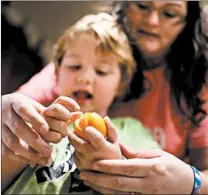  ??  ?? Jaxtien Miller gets help peeling a piece of fruit from his mother, Mercedes Boden, after a physical therapy session.