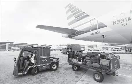  ?? Allen J. Schaben Los Angeles Times ?? A VEHICLE PULLS luggage unloaded from an American Airlines plane at Los Angeles Internatio­nal Airport in December. American and other airlines are seeing higher costs for labor, fuel and maintenanc­e while finding it difficult to raise airfares.